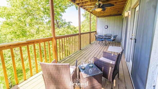 Eine überdachte Terrasse im Freien mit Holzbalkonen, Korbmöbeln und Deckenventilator.