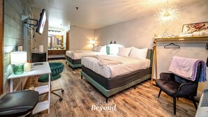 Habitación de hotel con dos camas, un escritorio con lámpara, una silla y un sillón colgante con una toalla.