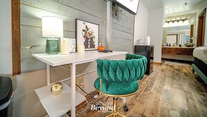 Una habitación moderna con un escritorio blanco, una silla verde, un cuadro enmarcado y un televisor montado en la pared.