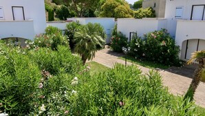 A courtyard with white buildings, lush greenery, and a pathway. - Beach Cannes Bungalows (Le Cannet)