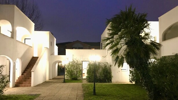 A modern building with a central courtyard, a staircase, and a palm tree. - Beach Cannes Bungalows (Le Cannet)