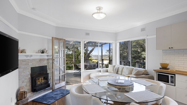 A modern living room with a fireplace, a glass dining table, and a sofa. - Secluded Family Retreat, Moments To Macs Beach (Macmasters Beach)