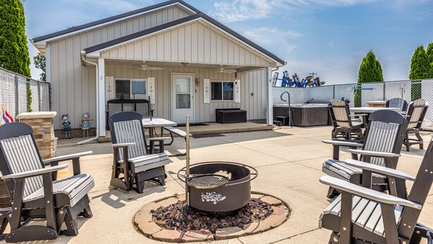 An outdoor patio area with Adirondack chairs, a fire pit, and a grill station.