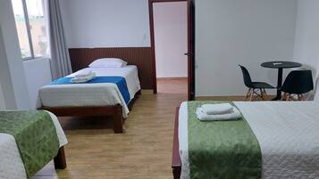 Habitación de hotel con dos camas, una mesita y sillas.