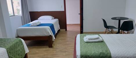 Habitación de hotel con dos camas, una mesita y sillas.