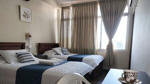 A hotel room with two beds, a table with a plate of food, and a chair. - Hotel Islas Galapagos (Puerto Baquerizo Moreno)
