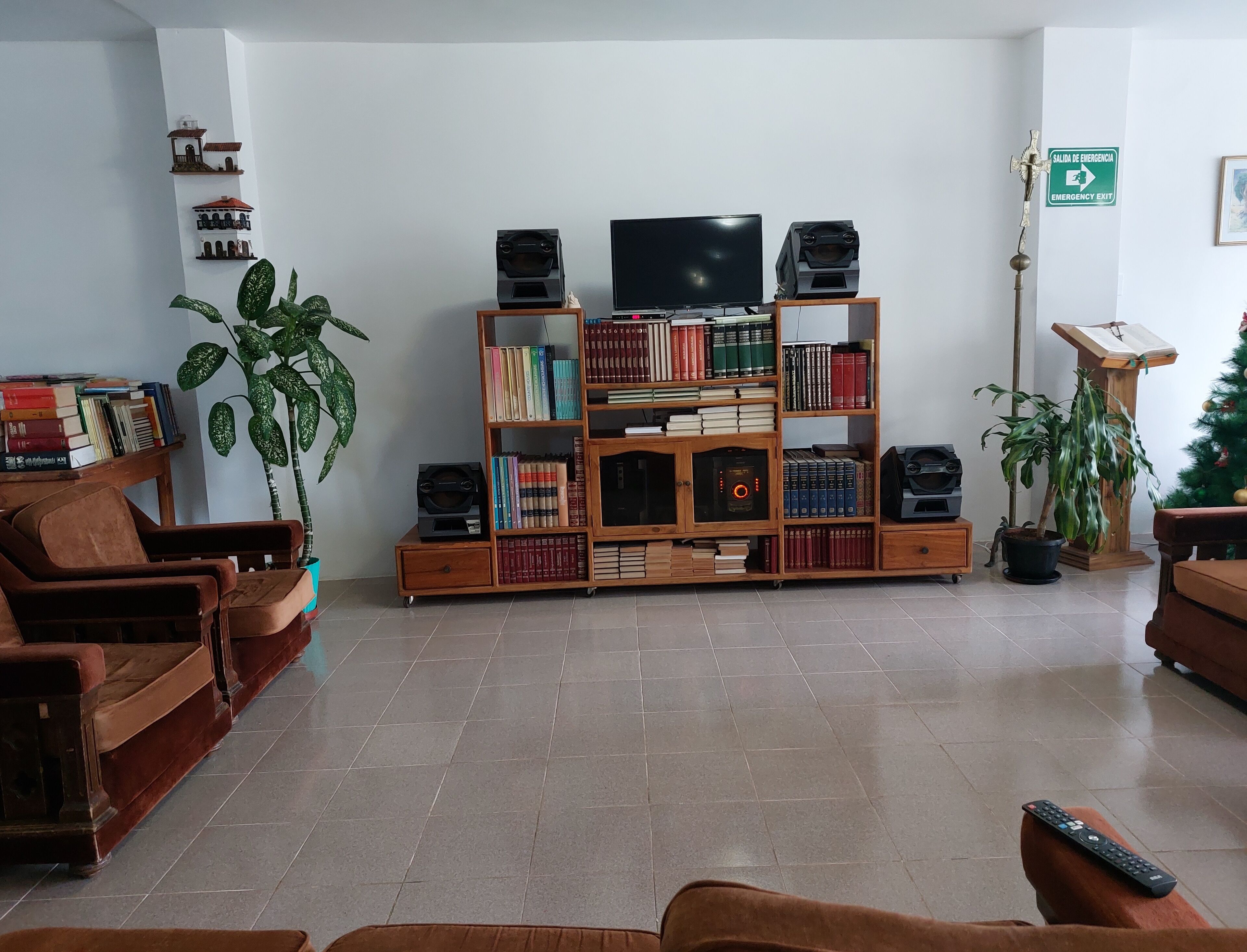 A living room with a wooden bookshelf, a television, and two brown leather sofas.