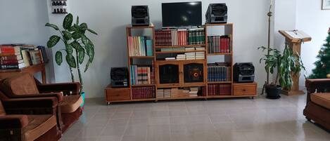 A living room with a wooden bookshelf, a television, and two brown leather sofas.