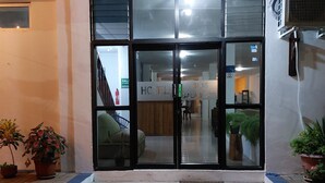 A hotel entrance with a glass door, potted plants, and a tiled floor. - Hotel Islas Galapagos (Puerto Baquerizo Moreno)