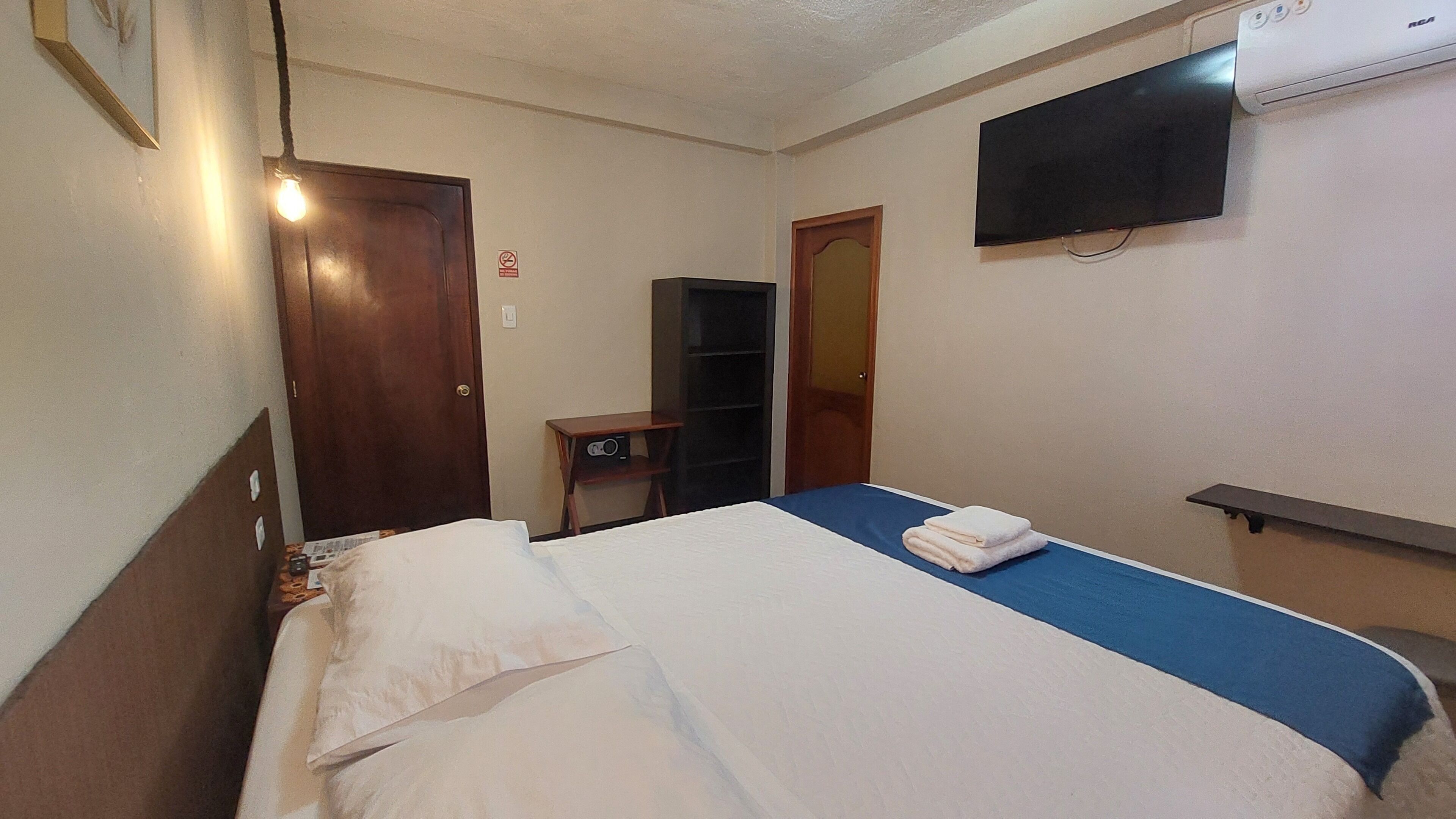 A hotel room with a bed, a TV, a desk, and a wardrobe.