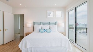 Une chambre à coucher avec un grand lit, deux tables de chevet, une fenêtre donnant sur un beau paysage et une porte menant à une autre pièce.