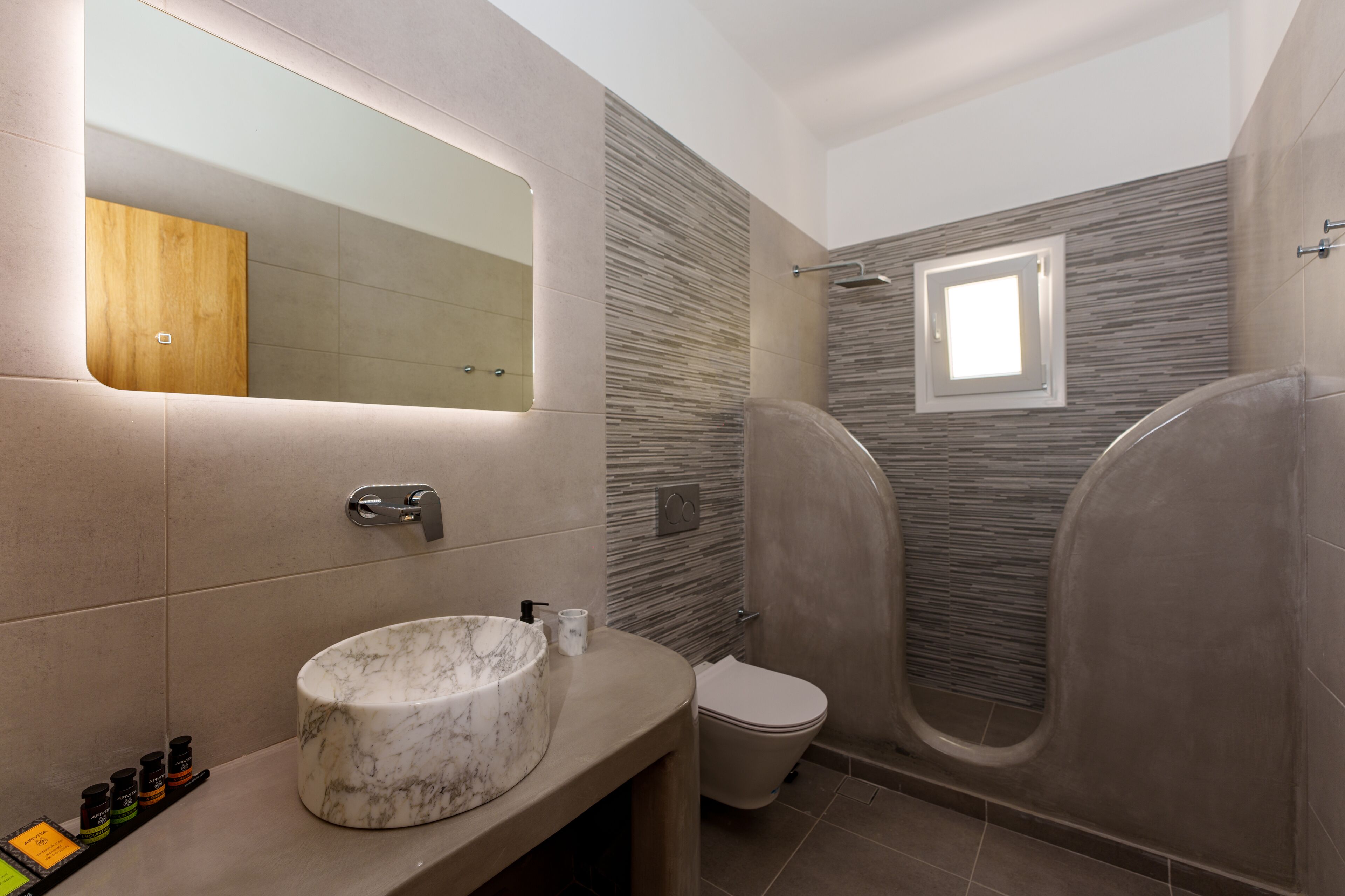 A modern bathroom with a marble sink, a toilet, and a shower area.