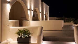 Hotel com design arquitetônico moderno, apresentando passarelas arqueadas e um vaso com planta em primeiro plano.