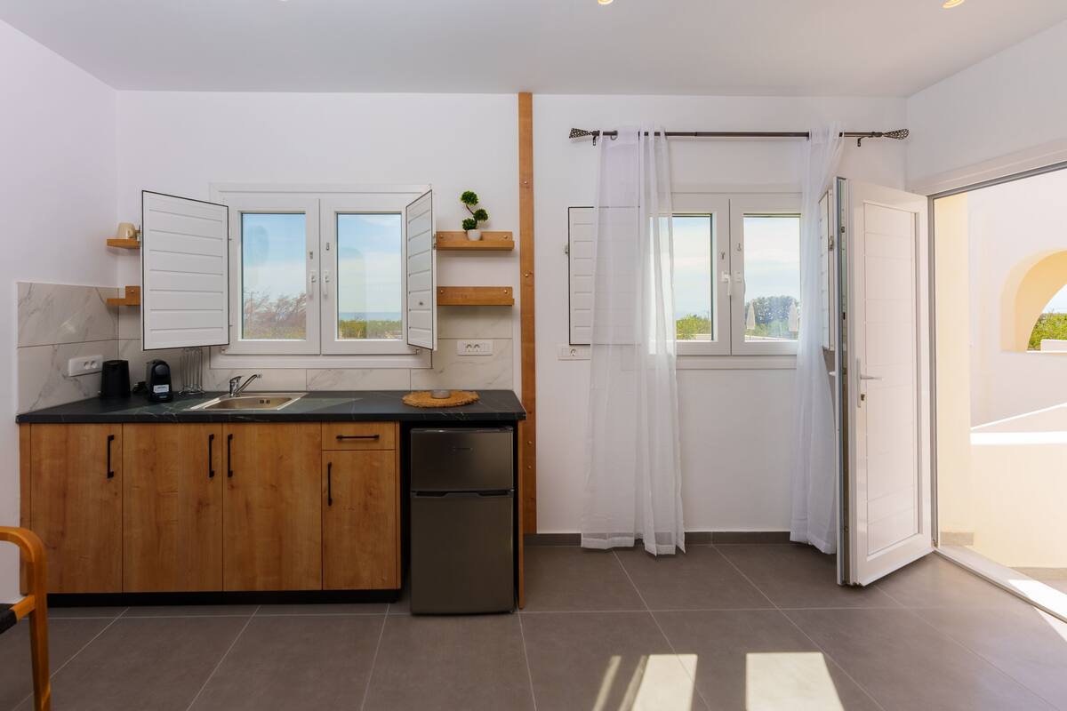 A modern kitchen with wooden cabinets, a built-in oven, and a window with curtains.