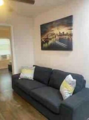 Relax in this inviting living room with a sofa, painting, and door leading to more space.