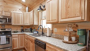 A kitchen with wooden cabinets, a granite countertop, a dishwasher, a coffee maker, and a toaster.