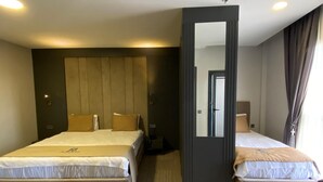 Une chambre d’hôtel avec deux lits, un grand miroir et une vue sur le couloir.