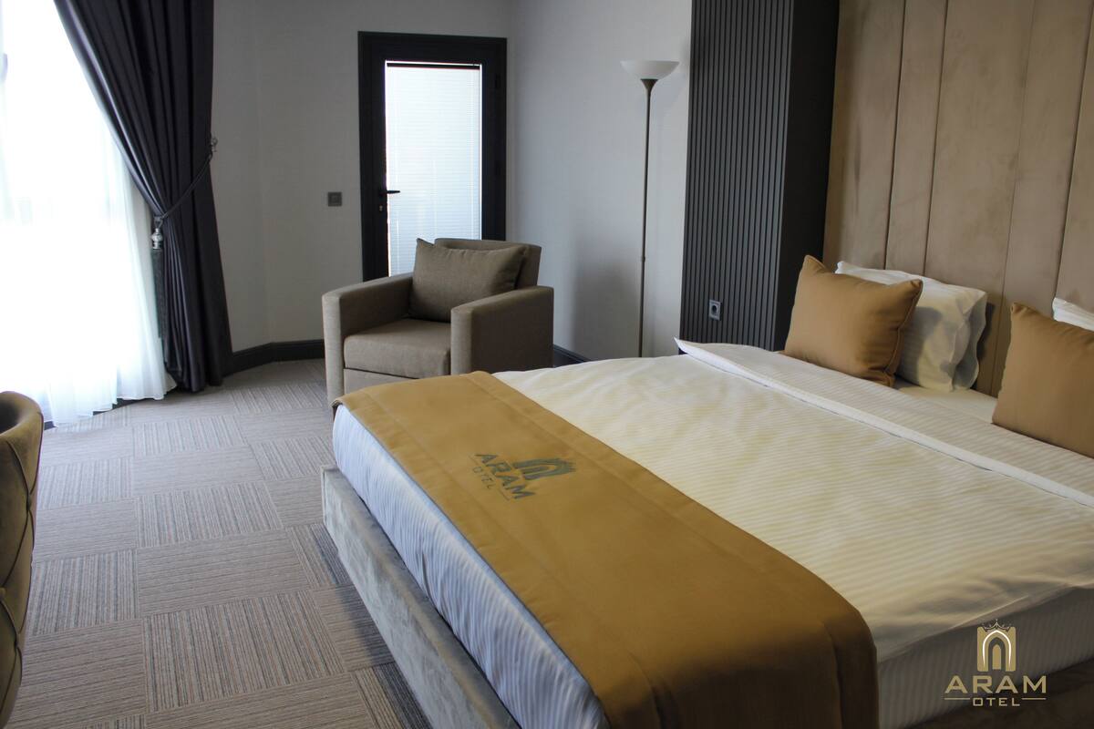 A hotel room with a large bed, a chair, a desk, and a lamp.