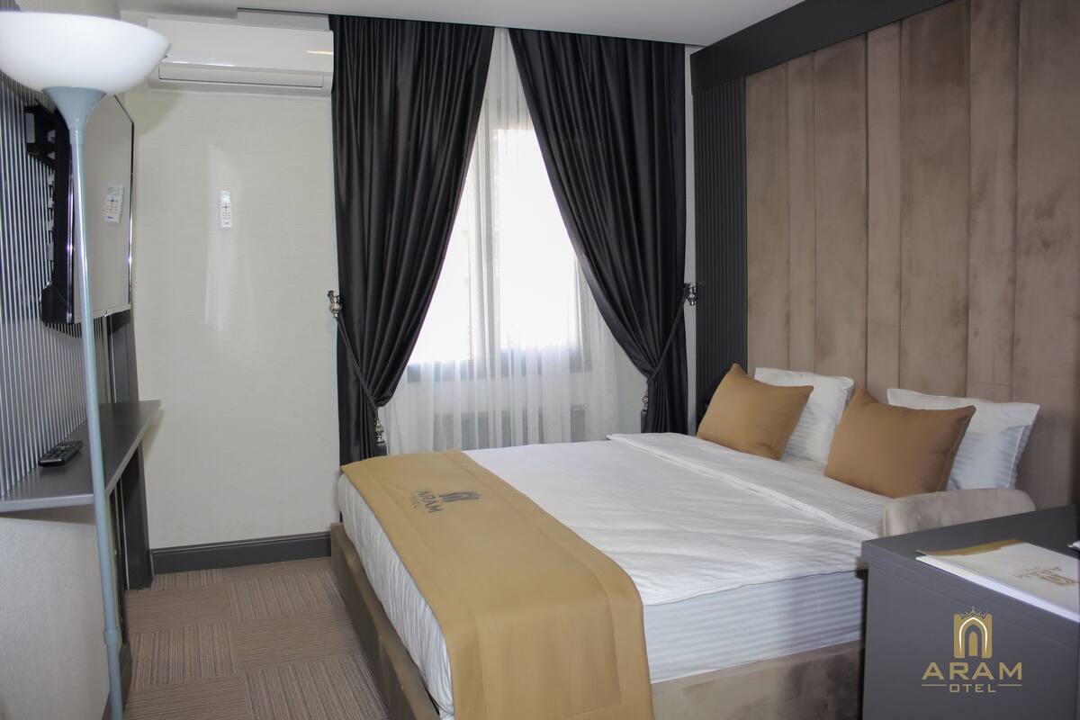 A hotel room with a bed, a desk, a lamp, and a wardrobe.