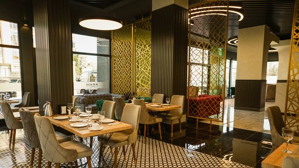 Un restaurant moderne avec un sol à motifs géométriques, des tables en bois et des chaises rembourrées.