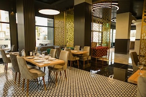 Un restaurante moderno con suelo de patrón geométrico, mesas de madera y sillas tapizadas.