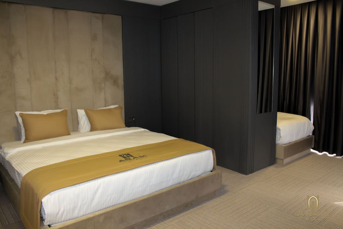 A modern hotel room with a large bed, a wardrobe, and a mirror.