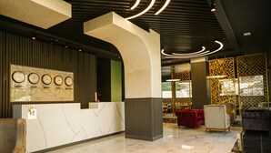 Un hall d’entrée moderne avec un comptoir d’accueil, une horloge murale et un espace détente avec des canapés.