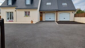 Ein zweistöckiges Haus mit Garage, kleiner Veranda und einem Blumentopf.