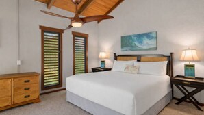 A bedroom with a bed, two nightstands, a ceiling fan, a wooden dresser, and a painting on the wall.