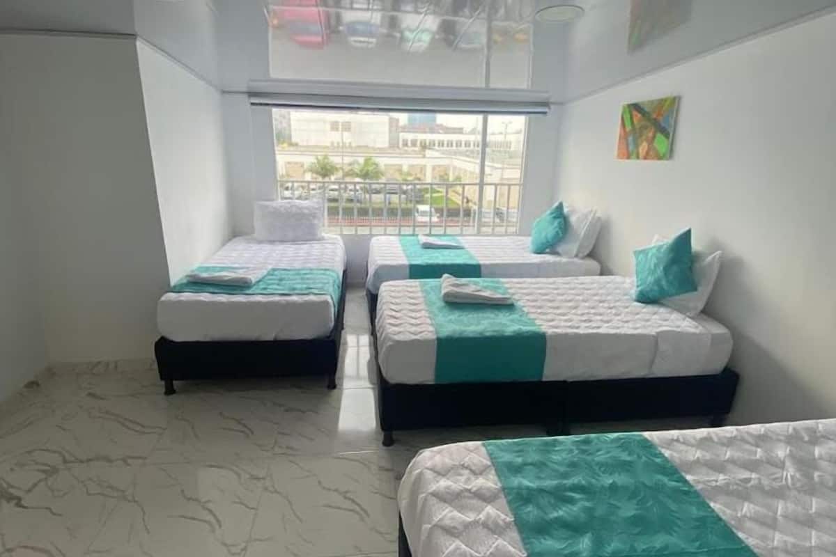 A hotel room with two beds, a balcony, and a city view.