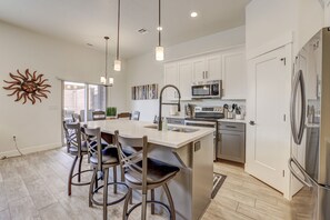 Una cocina moderna con una isla central, electrodomésticos de acero inoxidable y un adorno de sol en la pared.