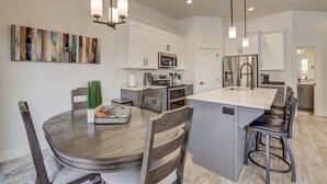 Une cuisine moderne avec des meubles blancs, des appareils en acier inoxydable et un îlot central doté de tabourets de bar.