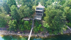 A wooden deck with a staircase leading to a building surrounded by dense trees. - Central Perk - pet friendly, luxury cabin feel,  coffee! (Crane Hill)
