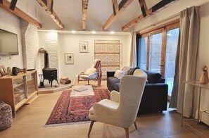 Cozy living room with a fireplace, comfortable seating area, and large window.