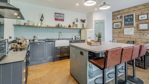 Cozinha moderna com ilha central, banquetas e área de jantar.