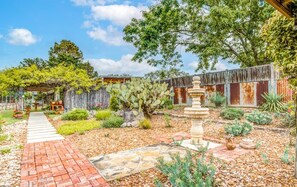 A garden with a cactus, a fountain, and a brick pathway. - Mucho Gusto in Bandera (Bandera)