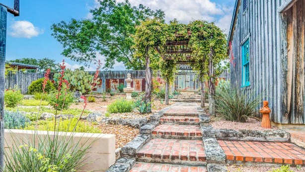 A garden with a stone pathway leading to a wooden pergola. - Mucho Gusto in Bandera (Bandera)