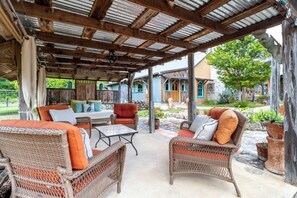 An outdoor patio with wicker furniture and a covered area with a corrugated metal roof. - Mucho Gusto in Bandera (Bandera)