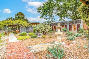 A garden with a paved pathway, cactus plants, and a rustic wooden fence. - Mucho Gusto in Bandera (Bandera)