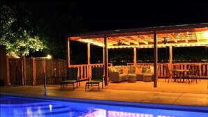 A covered outdoor seating area with a pool in the foreground. - Mucho Gusto in Bandera (Bandera)