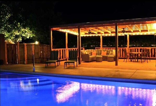 Relax in a shaded outdoor space with a sofa and chairs, adjacent to a swimming pool.