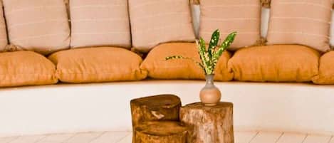 A living room with a sofa, a woven rug, and wooden stumps.