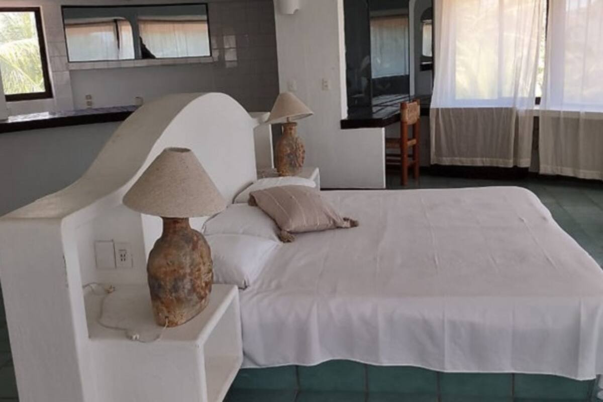 A bedroom with a large bed, two bedside lamps, a chair, and a television.