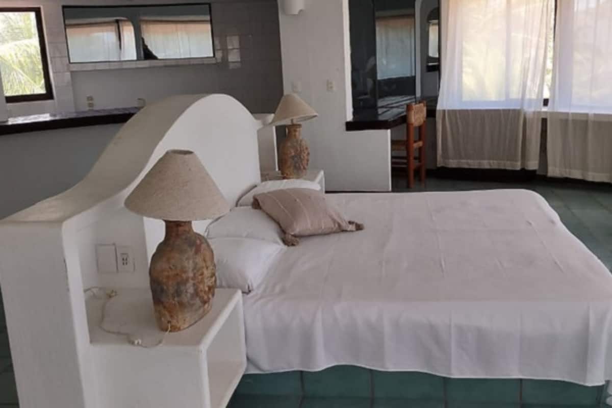 A bedroom with a large bed, two bedside lamps, a chair, and a TV.