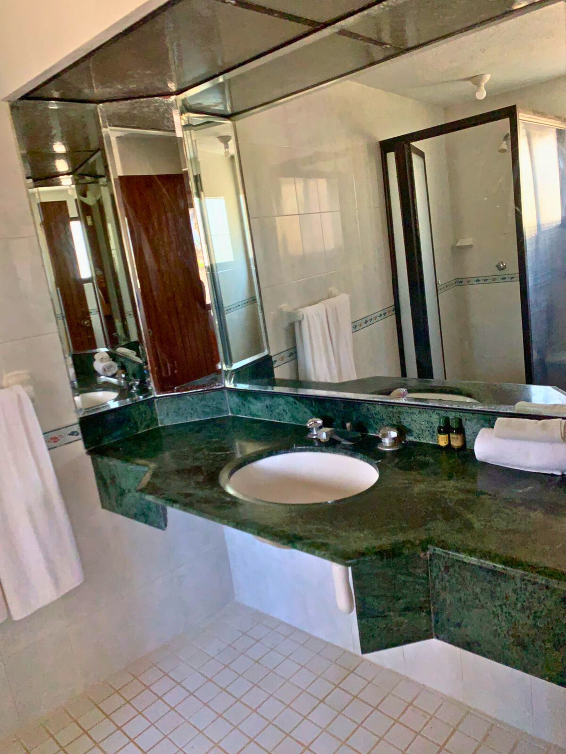 A bathroom with a large mirror, a sink, and a towel rack.