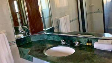 A bathroom with a large mirror, a sink, and a towel rack.