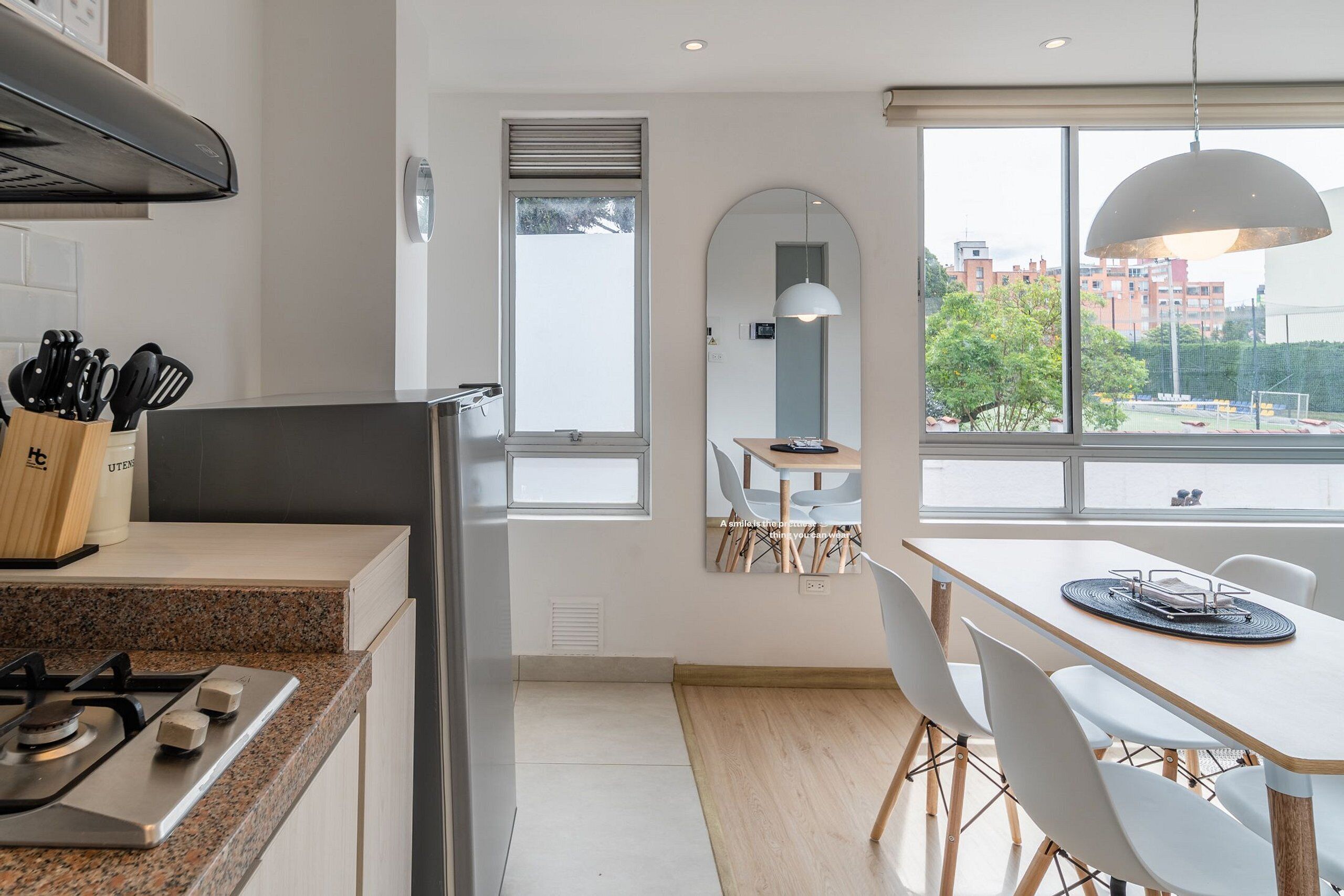 A modern kitchen with granite countertops, a gas stove, and a dining area with a white table and chairs.