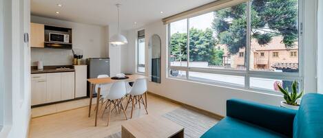 Un espacio habitable moderno con cocina, comedor y ventanas amplias que ofrecen vistas al exterior.