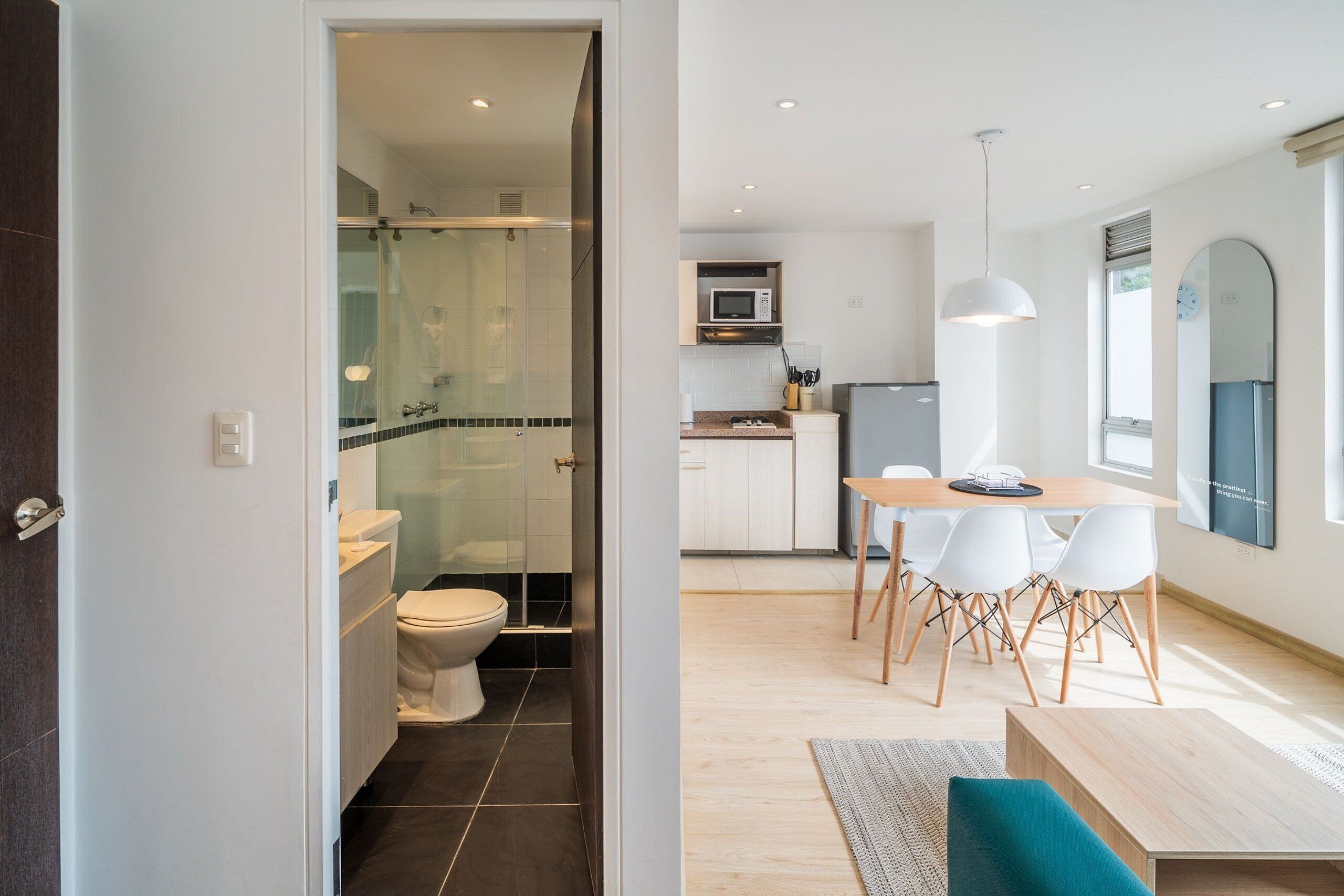 A modern kitchen with a microwave, refrigerator, and dining area with chairs and a table.