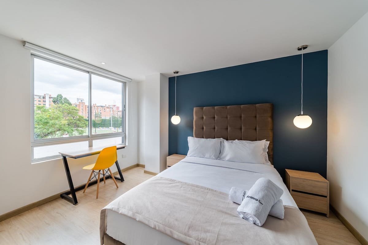 Une chambre d’hôtel moderne, dotée d’un grand lit, d’un bureau et d’une chaise.